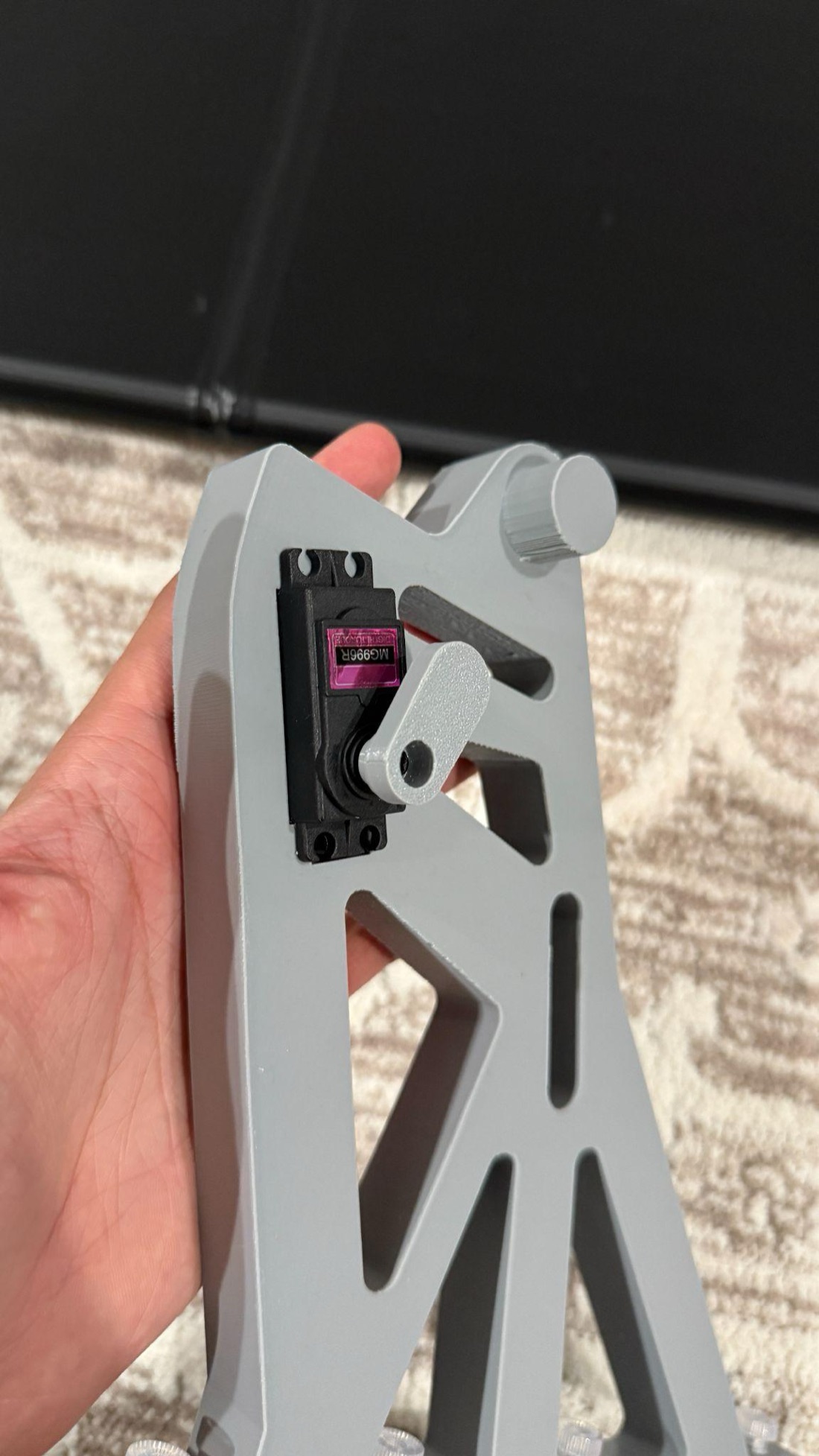 A printed support bracket held in hand, showing its open lattice structure